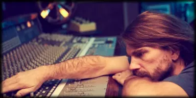 Ken Lewis leaning on an SSL console.